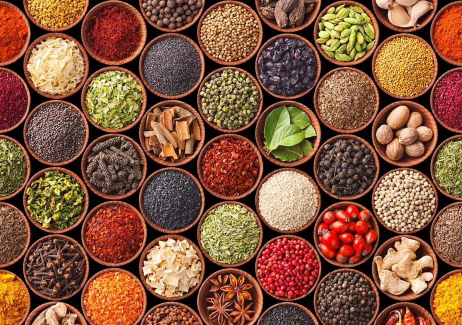 Dozens of small wooden bowls of whole and ground spices, photographed from above